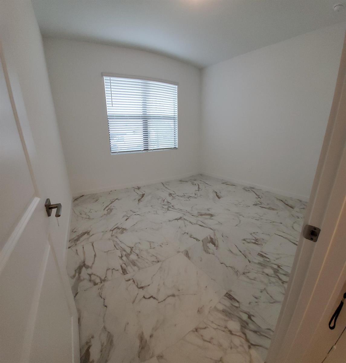 An empty room with white walls and large-format marble-look tile flooring — 1949 NE Ocean Dunes Drive, Jensen Beach FL 34957, JENSEN BEACH, FL