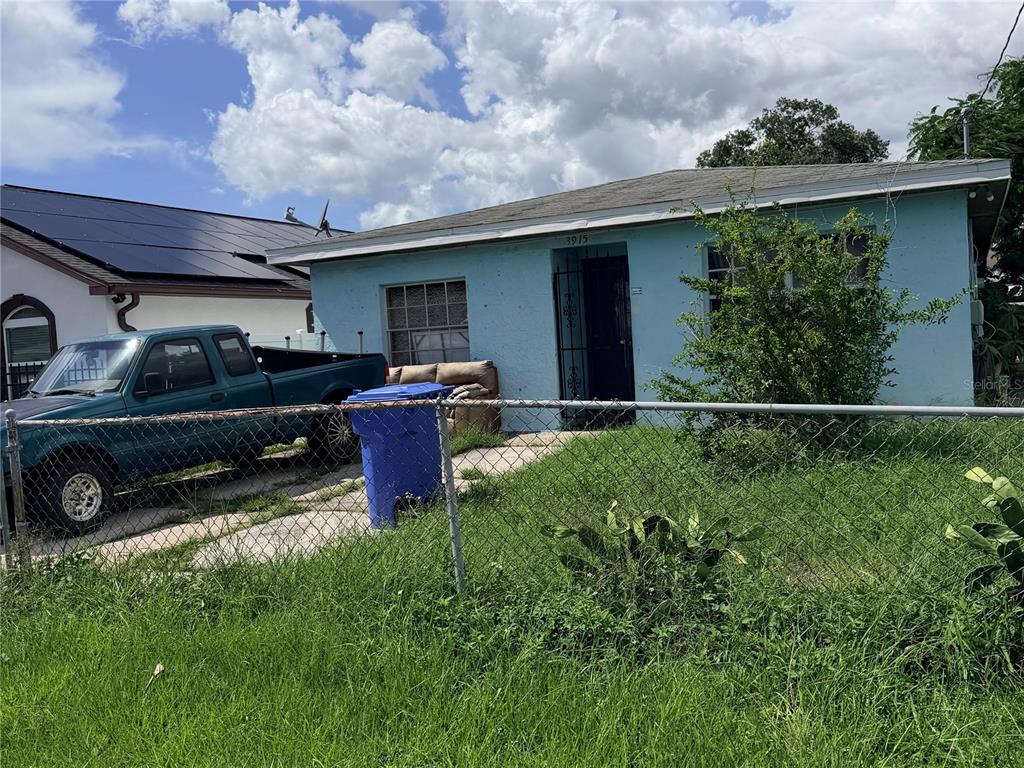 A light blue single-story house with a chain-link fence and a pickup truck parked outside — 3915 W BROAD STREET, TAMPA, FL