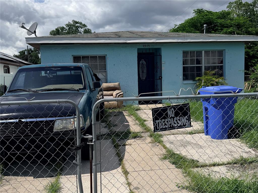 A light blue house features a chain-link fence, a parked truck, and a blue trash bin — 3915 W BROAD STREET, TAMPA, FL