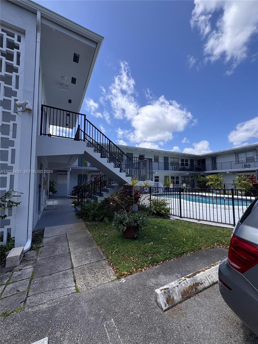 An exterior view of a two-story apartment building with an outdoor pool and staircase — 3510 Harrison St # 12, Hollywood FL 33021, HOLLYWOOD, FL