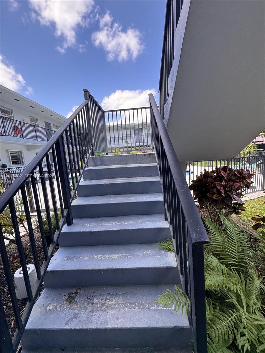 An outdoor staircase with black metal railings leads to an upper-level apartment walkway — 3510 Harrison St # 12, Hollywood FL 33021, HOLLYWOOD, FL