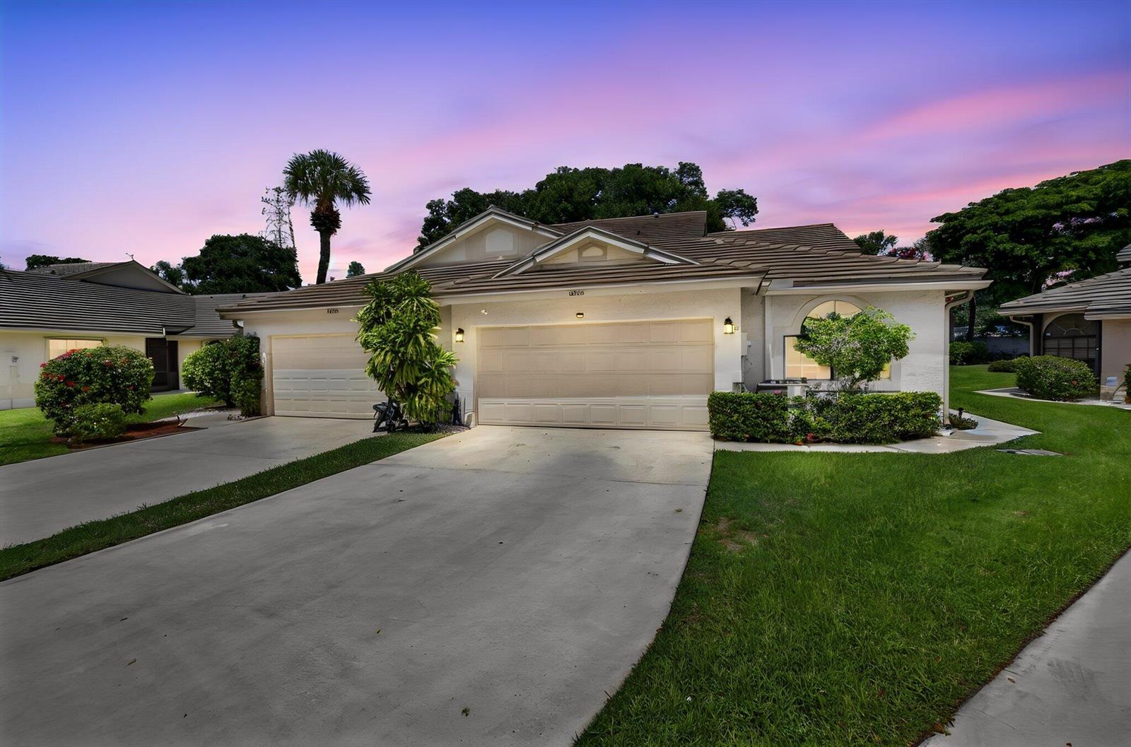 A single-story house with a two-car garage and a concrete driveway at sunset — 10984 Stafford Circle S, Boynton Beach FL 33436, BOYNTON BEACH, FL