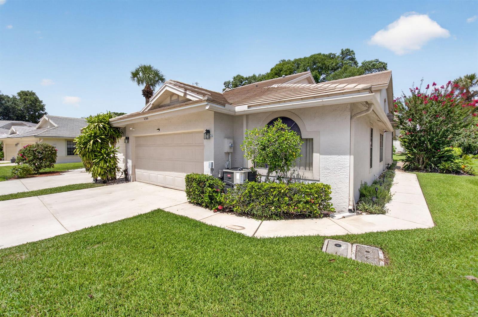 A single-story house with a beige stucco exterior, a two-car garage, and a landscaped yard — 10984 Stafford Circle S, Boynton Beach FL 33436, BOYNTON BEACH, FL