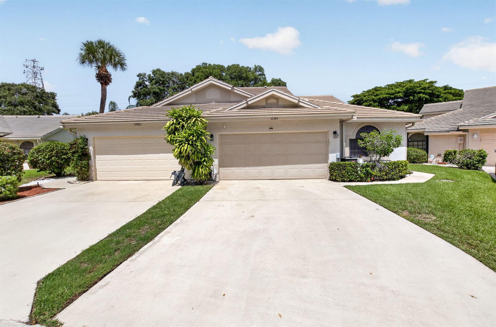 A single-story house with two garage doors, a concrete driveway, and a landscaped front yard — 10984 Stafford Circle S, Boynton Beach FL 33436, BOYNTON BEACH, FL