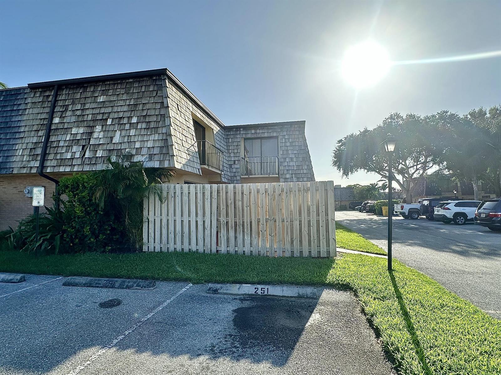 A two-story building with a shingled roof and a wooden fence stands by a parking lot — 251 Lake Arbor Drive, Palm Springs FL 33461, PALM SPRINGS, FL