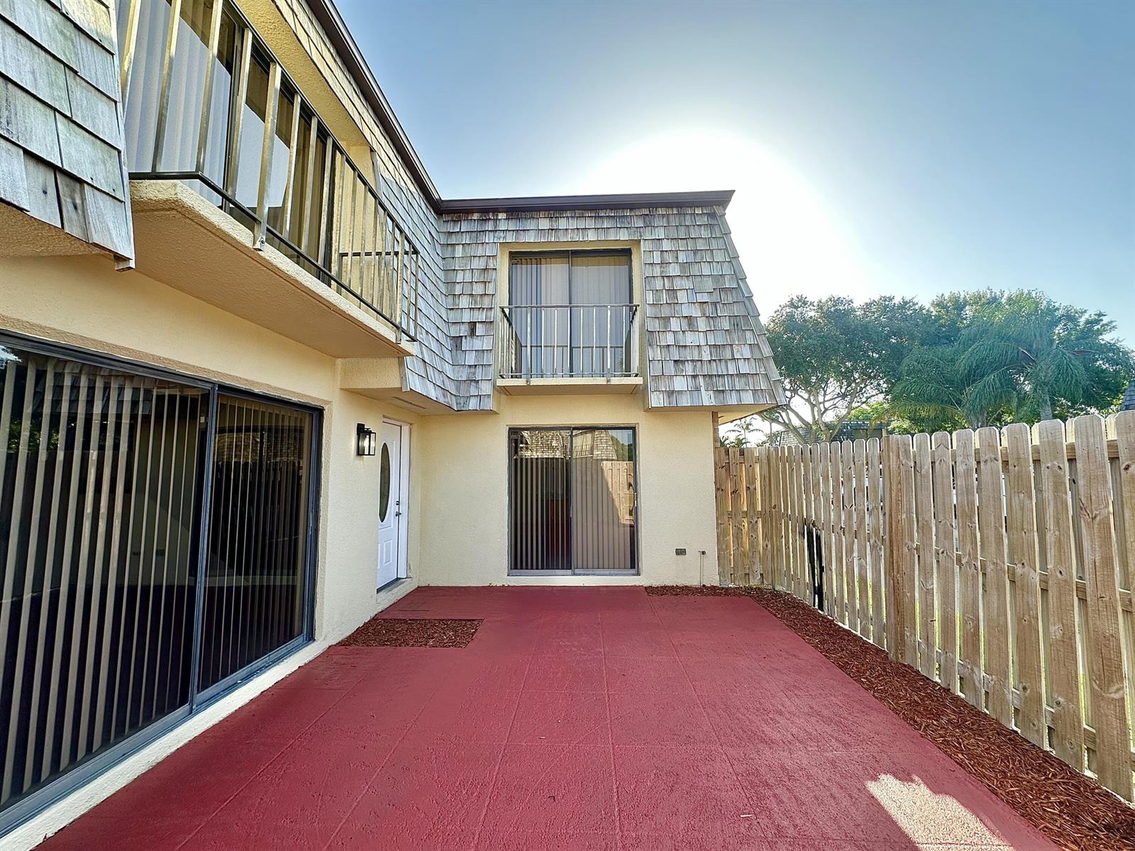 A red concrete patio sits outside a two-story building with a wooden shingle roof — 251 Lake Arbor Drive, Palm Springs FL 33461, PALM SPRINGS, FL