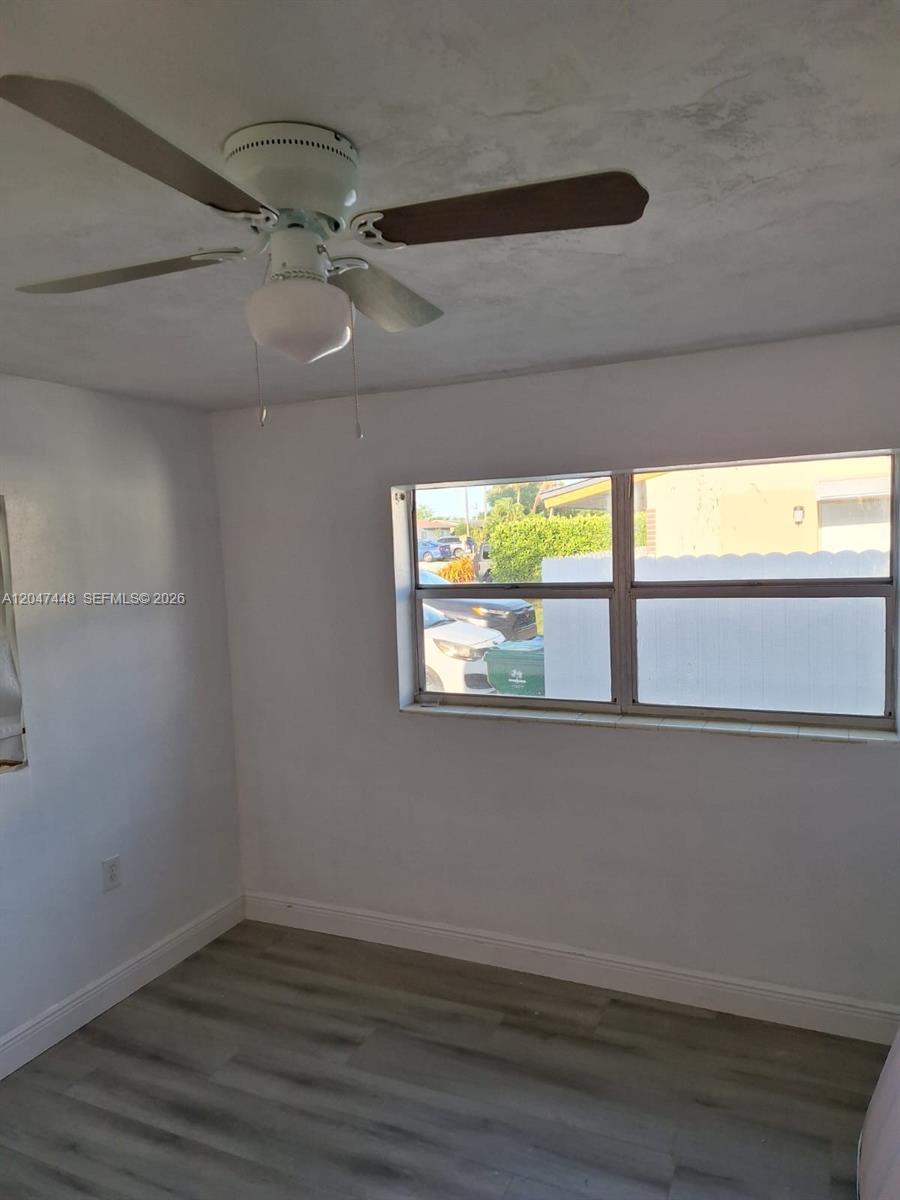 A bedroom with a ceiling fan, white walls, and wood-look flooring features a single window — 6328 SW 20th St, Miramar FL 33023, MIRAMAR, FL