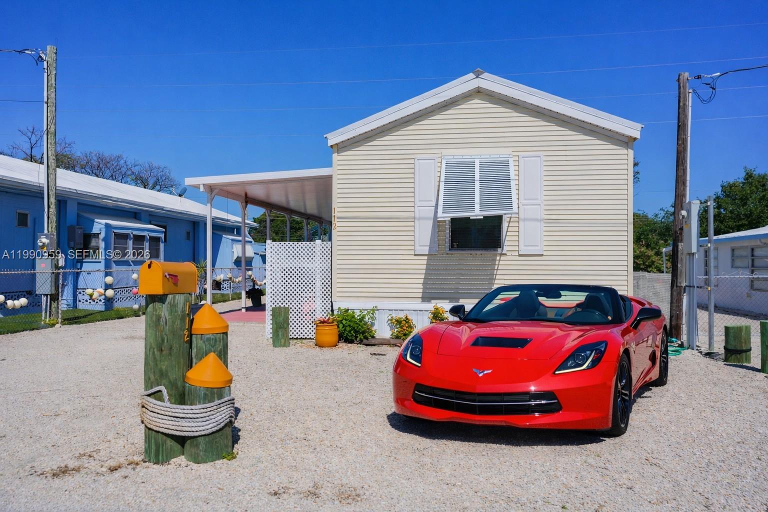 A red convertible sports car is parked on a gravel lot in front of a house — 112 Tweedy Pie Ter, Key Largo FL 33037, KEY LARGO, FL