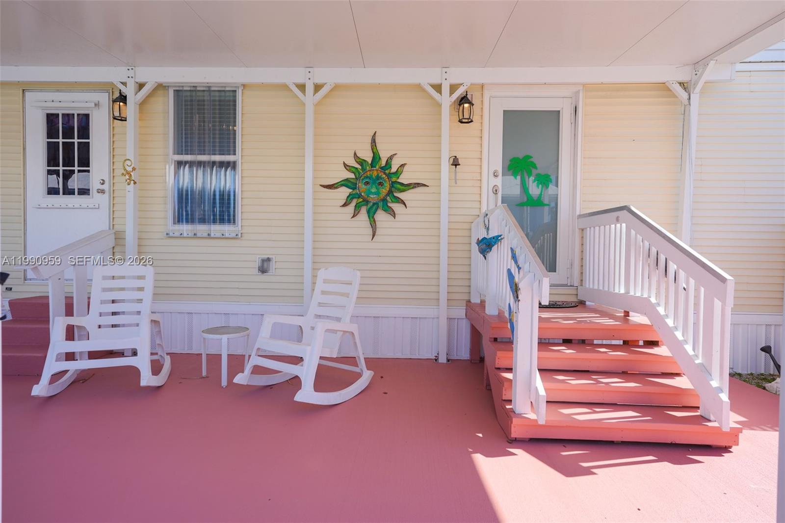 A covered porch features yellow siding, two white rocking chairs, and pink stairs — 112 Tweedy Pie Ter, Key Largo FL 33037, KEY LARGO, FL