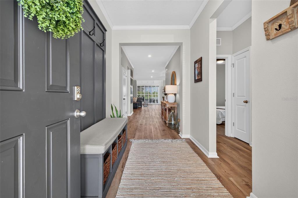 An entryway features a gray mudroom bench, wood flooring, and a view into the home — 8955 BOWER BASS CIRCLE, WESLEY CHAPEL, FL