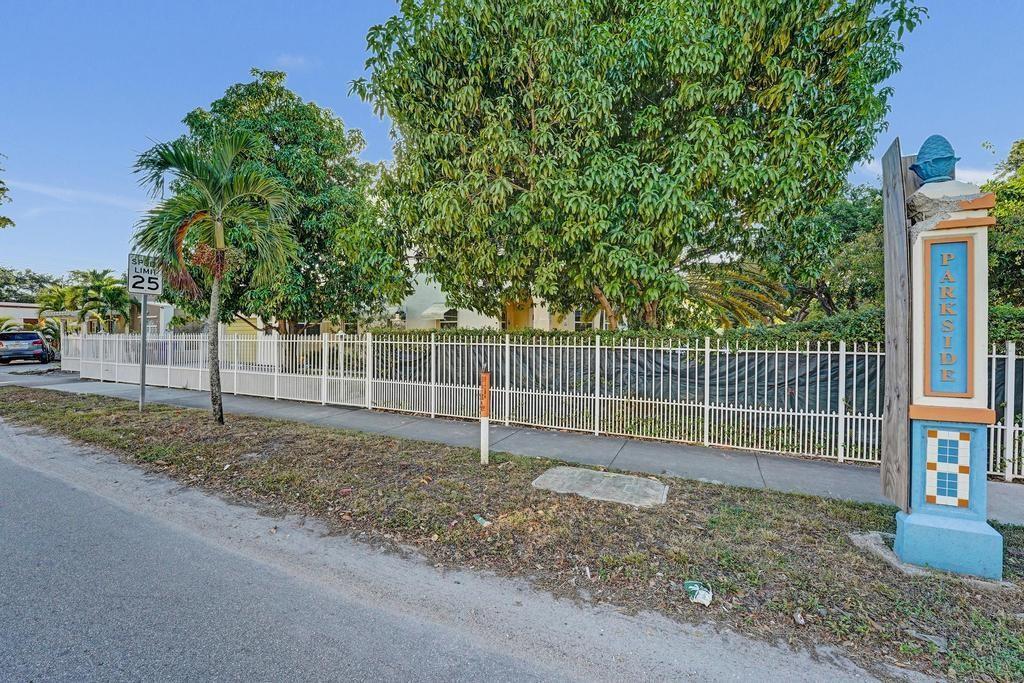 A white metal fence surrounds a property with mature trees and a Parkside community sign — 2000 Jackson Street, Hollywood FL 33020, HOLLYWOOD, FL