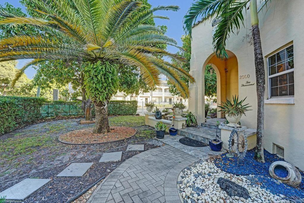 A paved walkway leads to the arched entrance of a stucco building with palm trees — 2000 Jackson Street, Hollywood FL 33020, HOLLYWOOD, FL