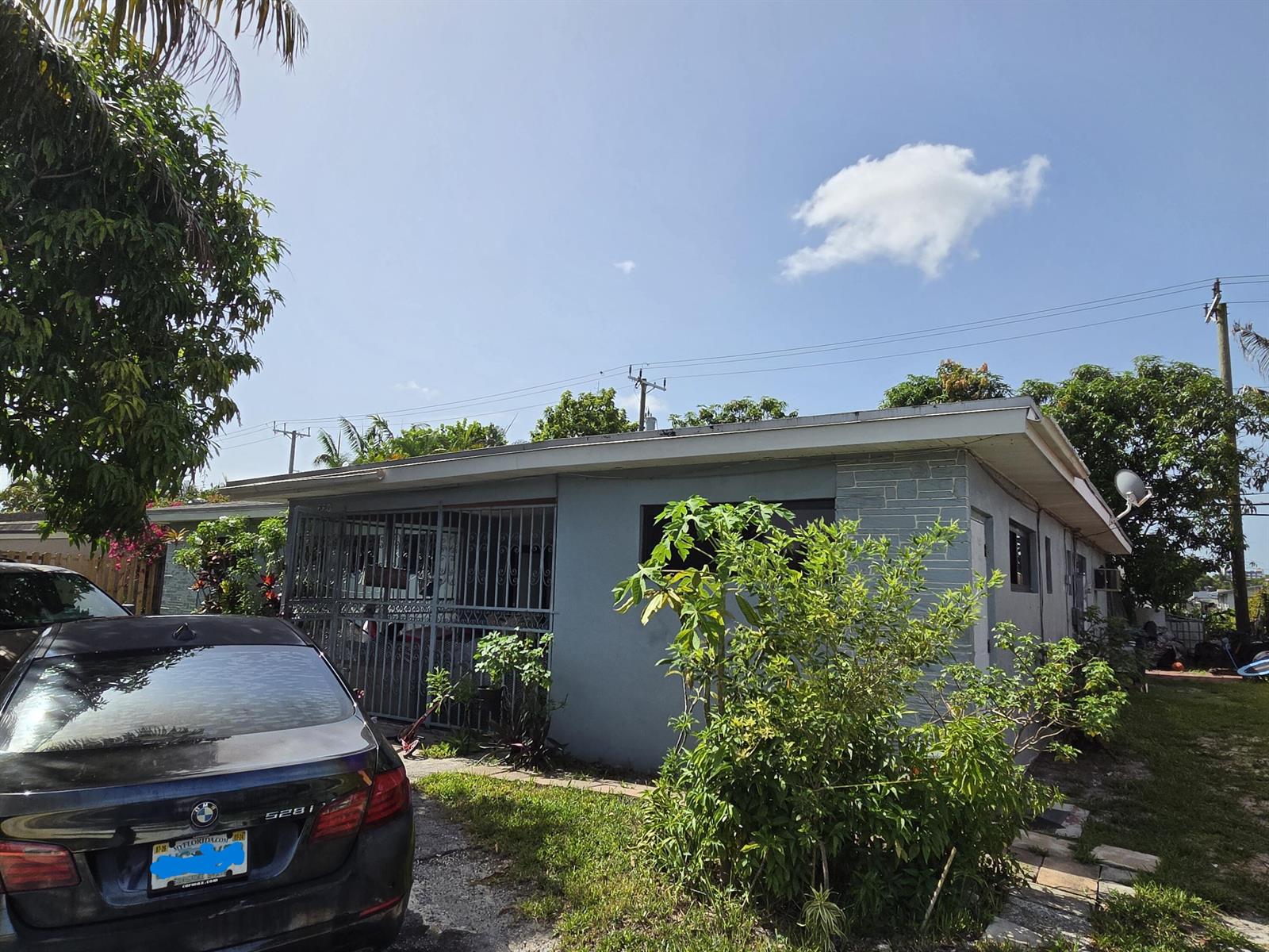 A single-story house with a grey exterior, a metal-gated porch, and a car parked outside — 660 NE 181ST Street, Miami FL 33162, MIAMI, FL