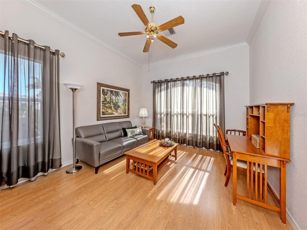 A living room with wood flooring, a grey sofa, a coffee table, and a wooden desk — 897 COLONIAL ROAD, VENICE, FL
