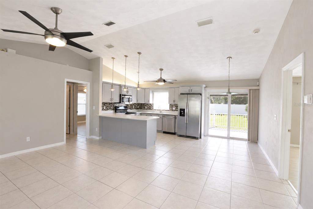 An open-concept kitchen with stainless steel appliances, a breakfast bar, and tile flooring — 4 SEVERN COURT, PALM COAST, FL