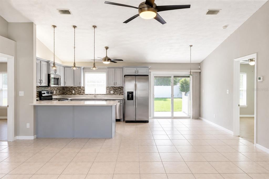 A kitchen with grey cabinets, stainless steel appliances, and a breakfast bar opens to a patio — 4 SEVERN COURT, PALM COAST, FL