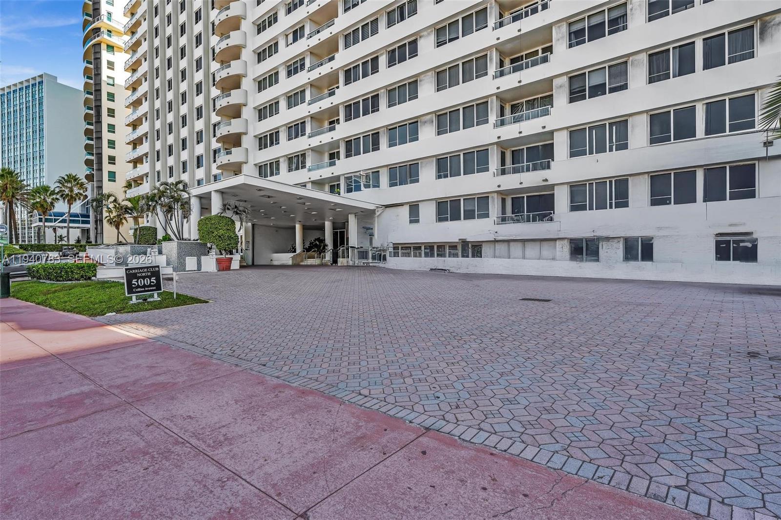 The exterior of a multi-story residential building features a paved driveway and a covered entrance — 5005 Collins Ave # 824, Miami Beach FL 33140, MIAMI BEACH, FL
