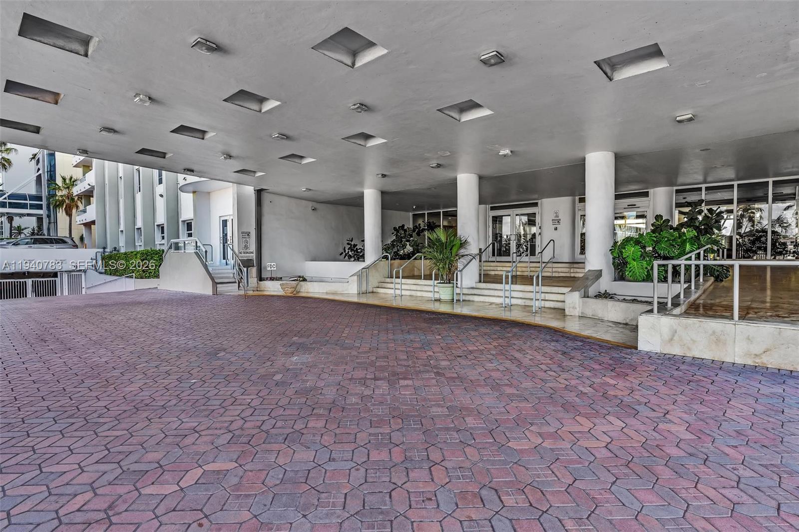 A paved driveway leads to the covered entrance of a building with white columns — 5005 Collins Ave # 824, Miami Beach FL 33140, MIAMI BEACH, FL