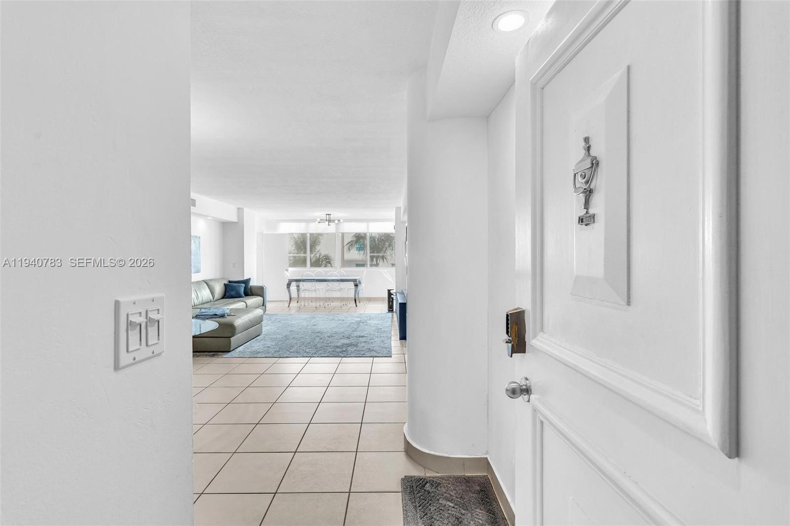 A white door opens into a tiled entryway leading to a living room with furniture — 5005 Collins Ave # 824, Miami Beach FL 33140, MIAMI BEACH, FL