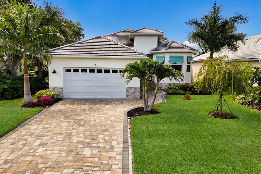 A single-story house with a white exterior, stone accents, a paved driveway, and palm trees — 115 WESTWIND DRIVE, PLACIDA, FL