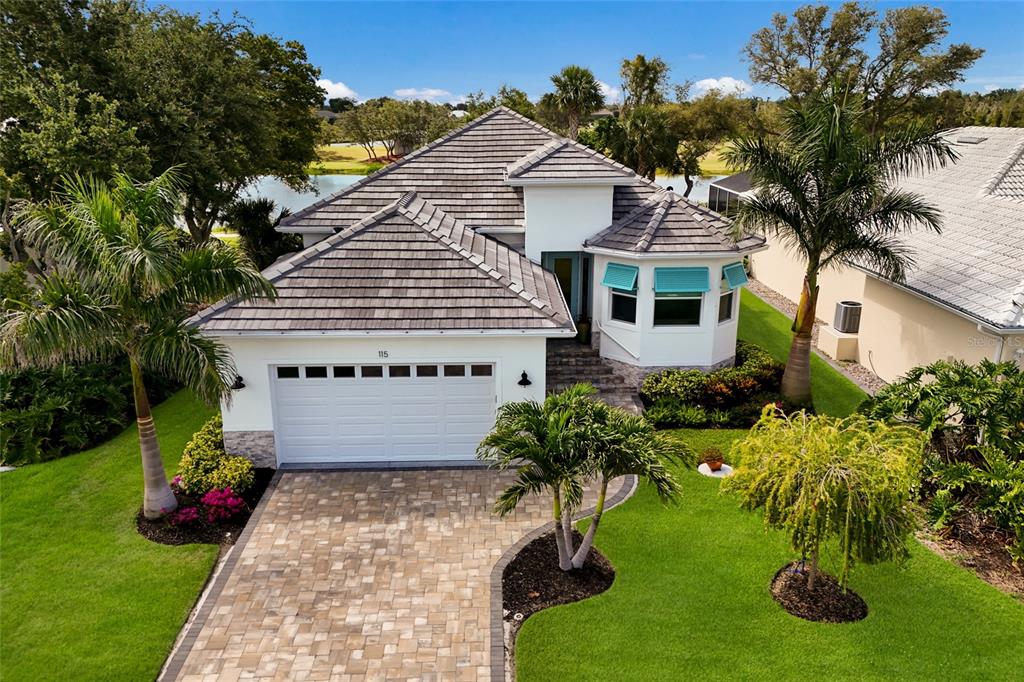 An elevated view of a single-story house with a tiled roof, paver driveway, and landscaping — 115 WESTWIND DRIVE, PLACIDA, FL