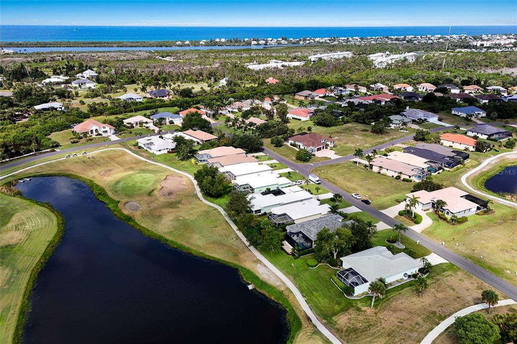 An aerial view shows a residential neighborhood with houses situated along a golf course pond — 115 WESTWIND DRIVE, PLACIDA, FL