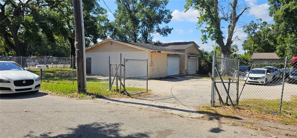 A single-story commercial building with two garage bays sits behind a chain-link fence — 5910 N 40TH STREET, TAMPA, FL