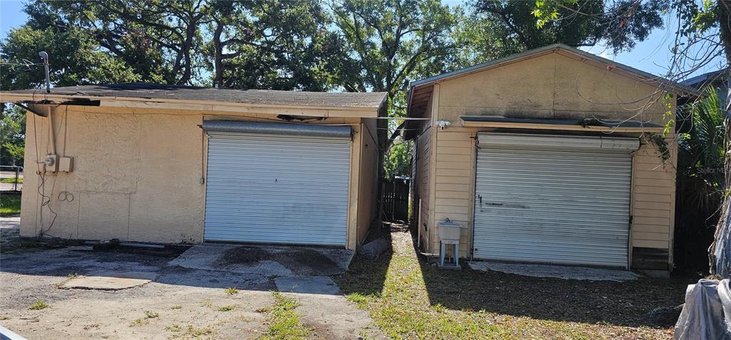 Two detached, light-colored storage buildings with roll-up metal doors stand side-by-side on a dirt lot — 5910 N 40TH STREET, TAMPA, FL