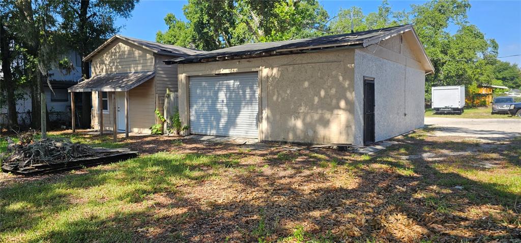 A tan detached garage with a roll-up door and a side entry door — 5910 N 40TH STREET, TAMPA, FL