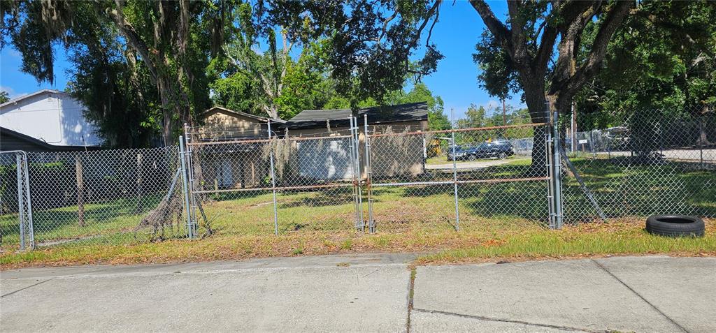 A chain-link fence encloses a grassy lot with a small building and mature trees — 5910 N 40TH STREET, TAMPA, FL
