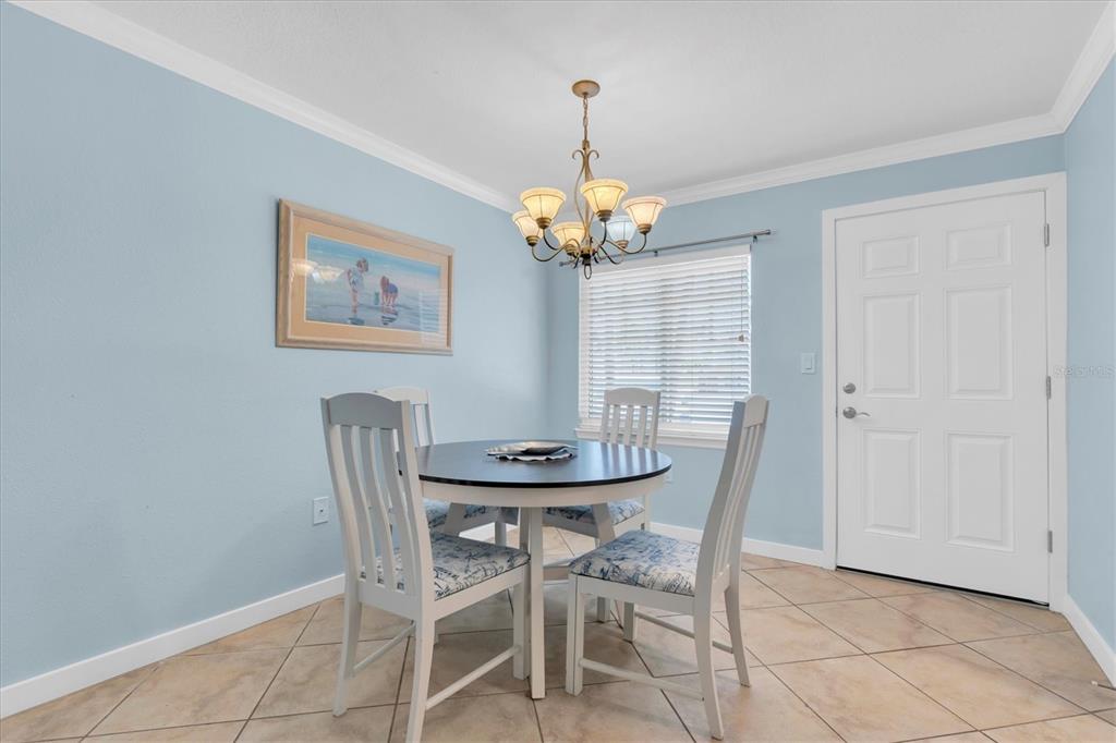 A dining area with light blue walls, a round table, four chairs, and tile flooring — 19417 GULF BOULEVARD UNIT E103, INDIAN ROCKS BEACH, FL