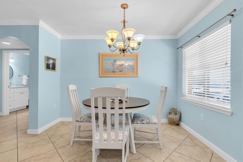 A dining room with light blue walls, a round table, and a chandelier — 19417 GULF BOULEVARD UNIT E103, INDIAN ROCKS BEACH, FL