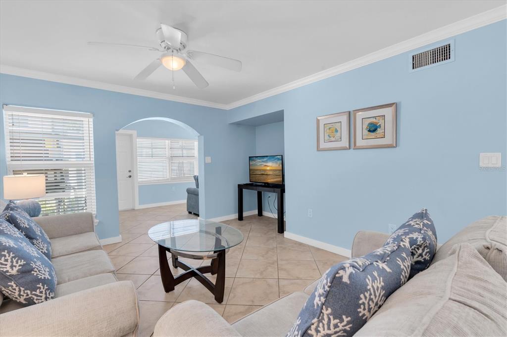 A living room with light blue walls, tile flooring, two sofas, and a glass coffee table — 19417 GULF BOULEVARD UNIT E103, INDIAN ROCKS BEACH, FL