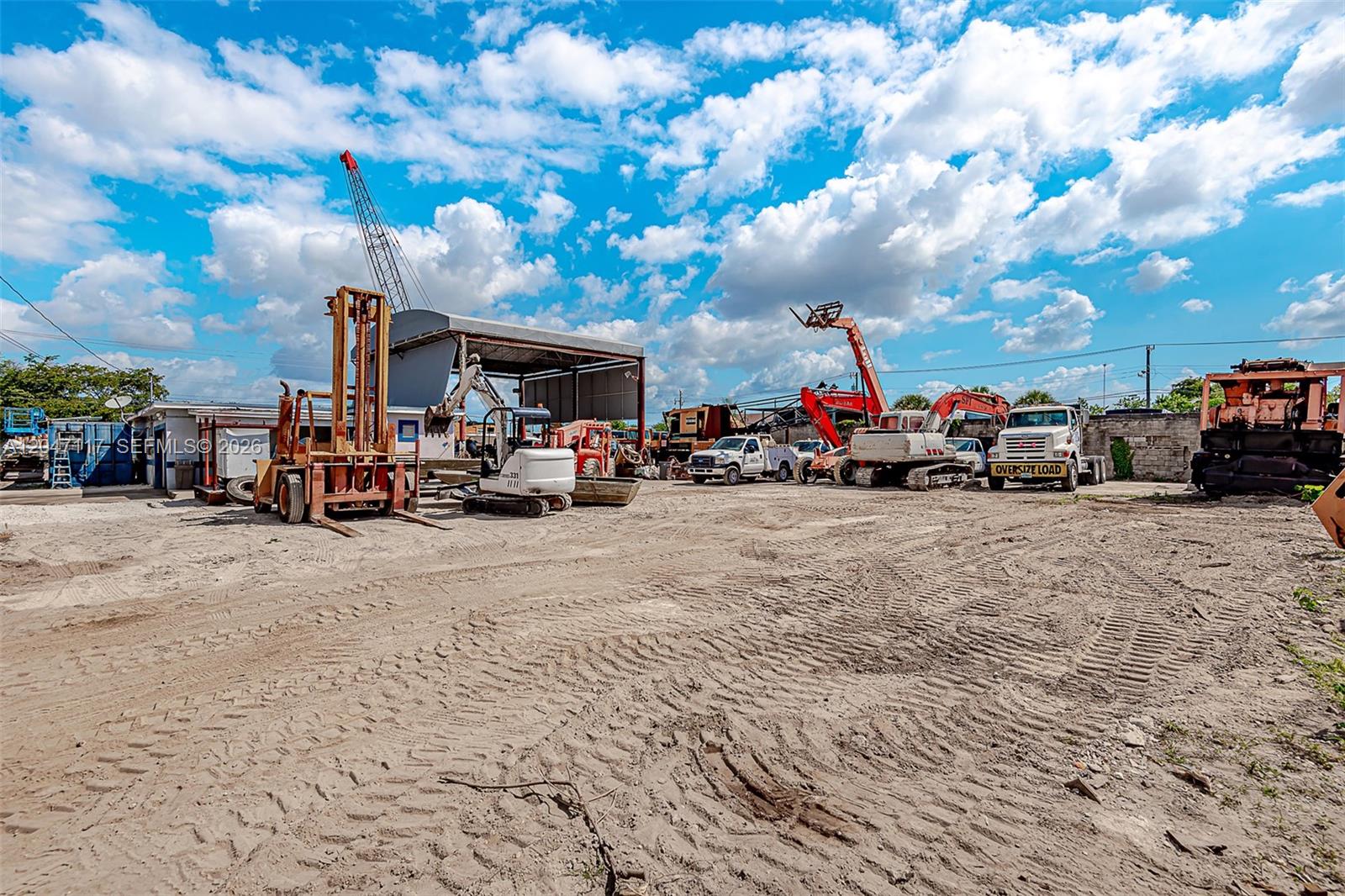 An outdoor construction equipment yard features various heavy machinery, trucks, and a metal structure — 2301 SW 57th Ave, West Park FL 33023, WEST PARK, FL