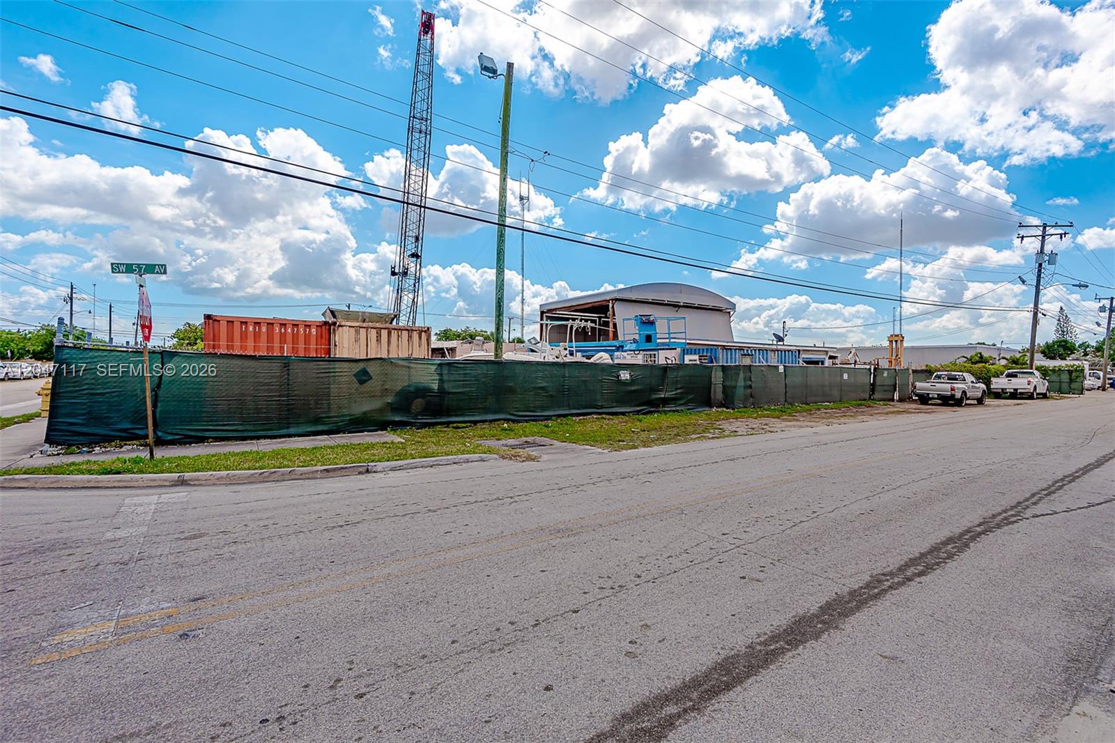 A fenced industrial lot features a crane, shipping containers, and a warehouse under a blue sky — 2301 SW 57th Ave, West Park FL 33023, WEST PARK, FL