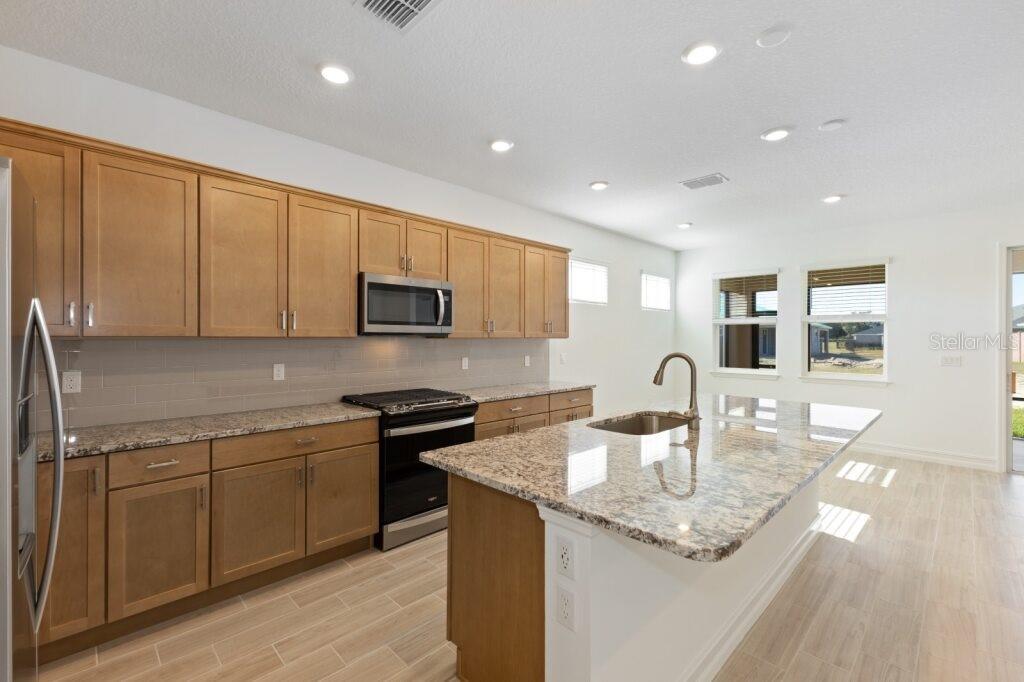 A kitchen with light wood cabinets, granite countertops, a center island, and stainless steel appliances — 3320 NW 52ND AVENUE ROAD, OCALA, FL