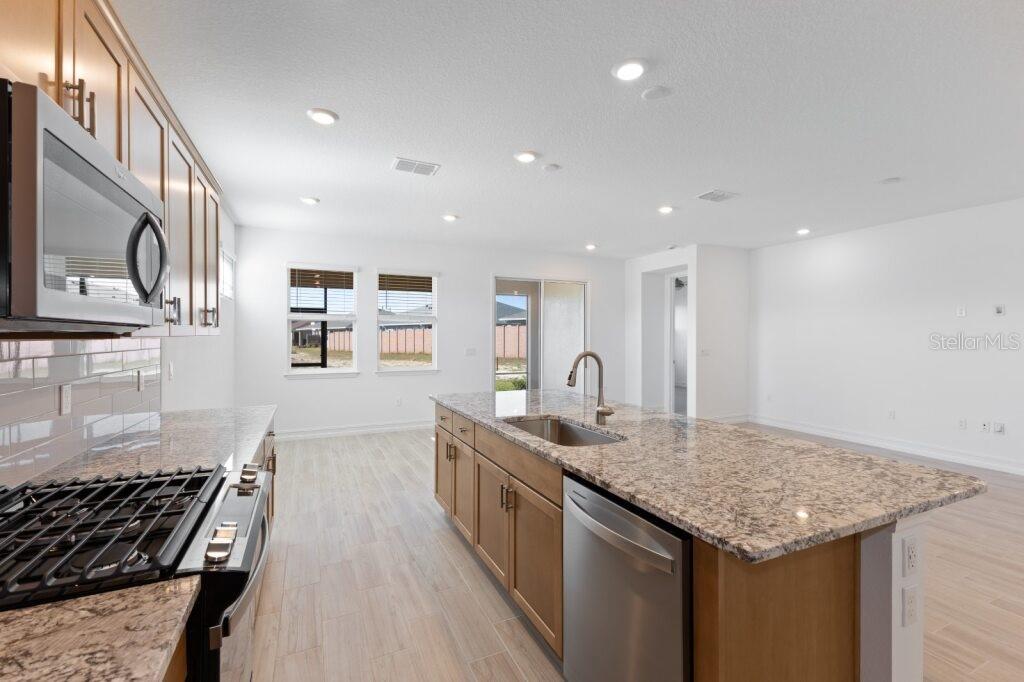 A kitchen with light wood cabinets, granite countertops, stainless steel appliances, and tile flooring — 3320 NW 52ND AVENUE ROAD, OCALA, FL