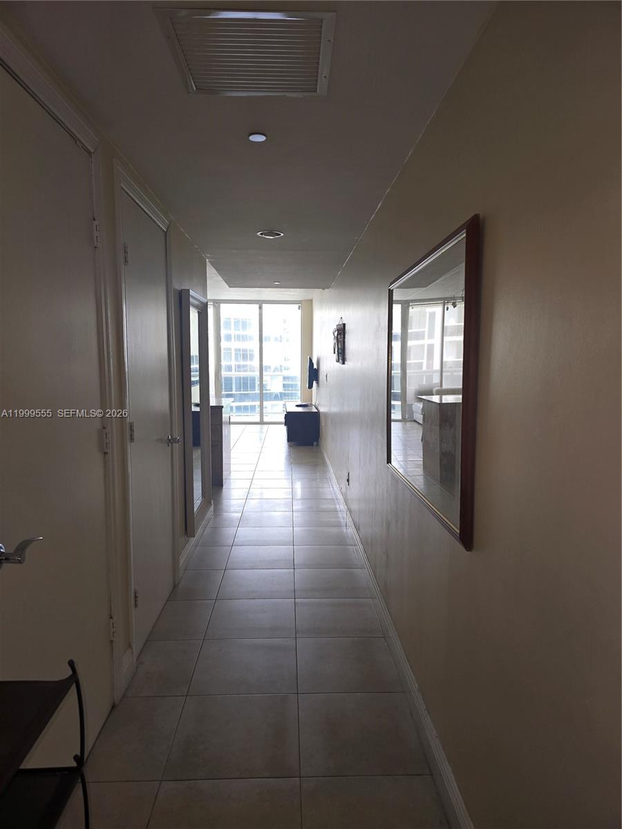 A long, tiled hallway leads toward a bright living area with floor-to-ceiling windows — 1830 S Ocean Dr # 4309, Hallandale Beach FL 33009, HALLANDALE BEACH, FL
