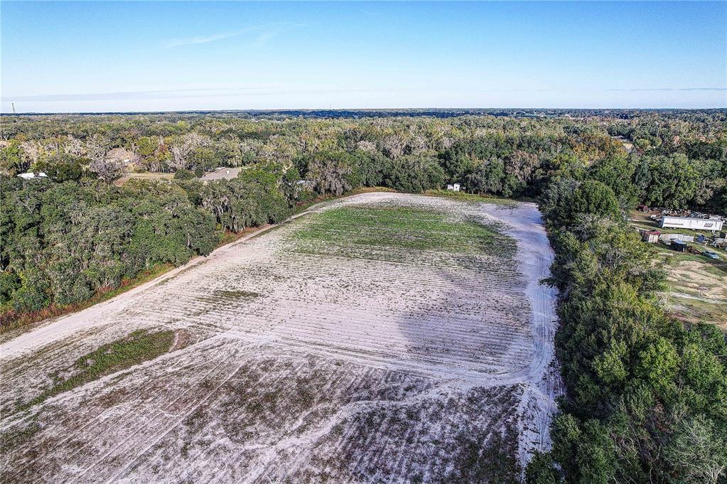 An aerial view shows a large, cleared rectangular field surrounded by dense green forest — 4822 NESMITH ROAD, PLANT CITY, FL