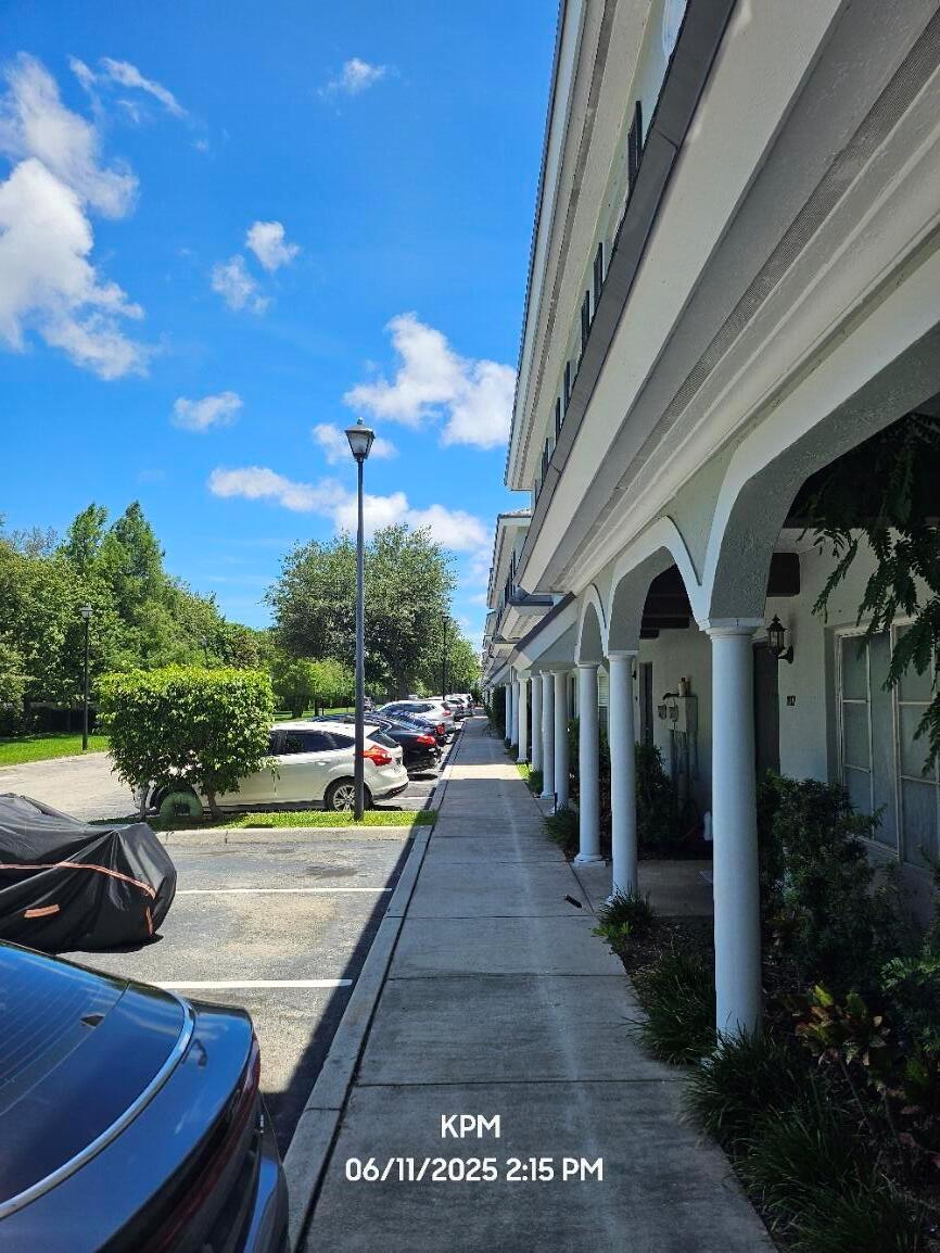 A sidewalk runs alongside a multi-unit building with white columns and arched entryways — 1193 Colonial Palms Way, Palm Springs FL 33406, PALM SPRINGS, FL