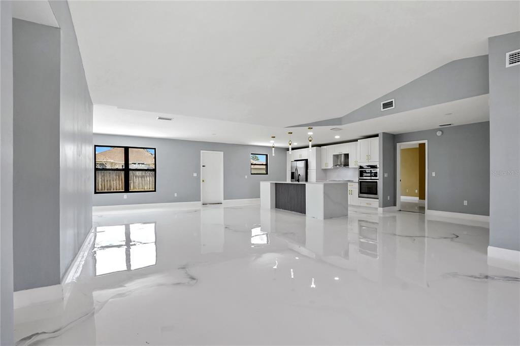 An open-concept kitchen and living area features white glossy floors and gray walls — 4209 SW TUSCOL STREET, PORT ST LUCIE, FL
