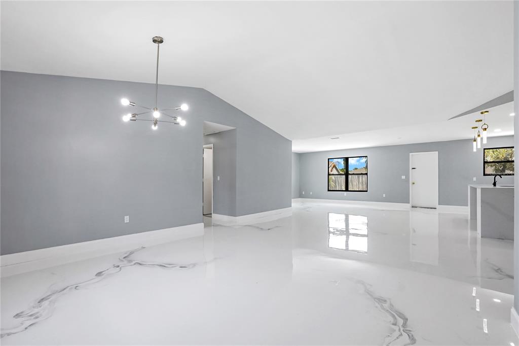 A bright, open-concept living area features gray walls, a modern chandelier, and white marble flooring — 4209 SW TUSCOL STREET, PORT ST LUCIE, FL