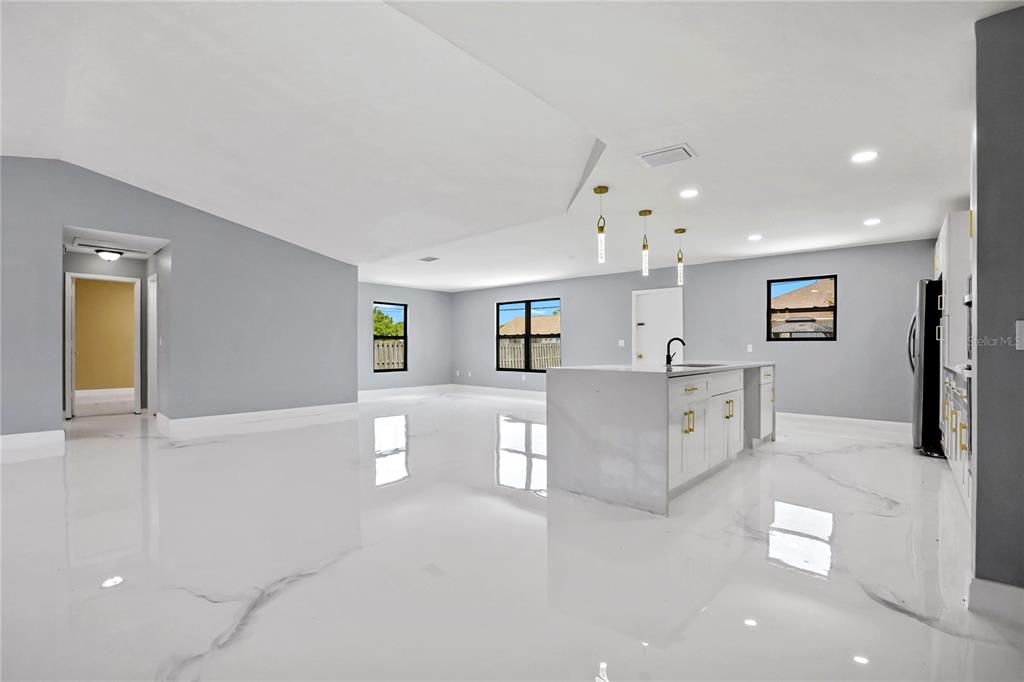 A modern open-concept kitchen and living area features white marble-look floors and a central island — 4209 SW TUSCOL STREET, PORT ST LUCIE, FL