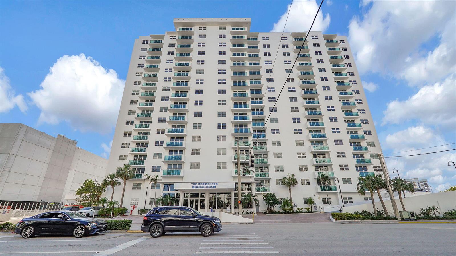 A multi-story residential building with balconies stands behind a street with a parked car — 3000 S Ocean Drive # 920, Hollywood FL 33019, HOLLYWOOD, FL