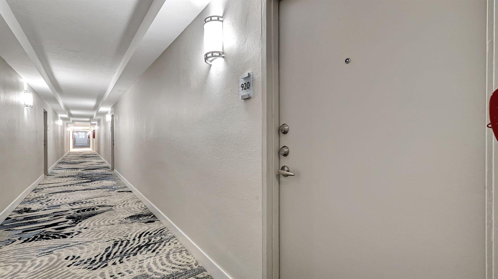 A hallway with patterned carpet leads to a door labeled 920 with multiple locks — 3000 S Ocean Drive # 920, Hollywood FL 33019, HOLLYWOOD, FL