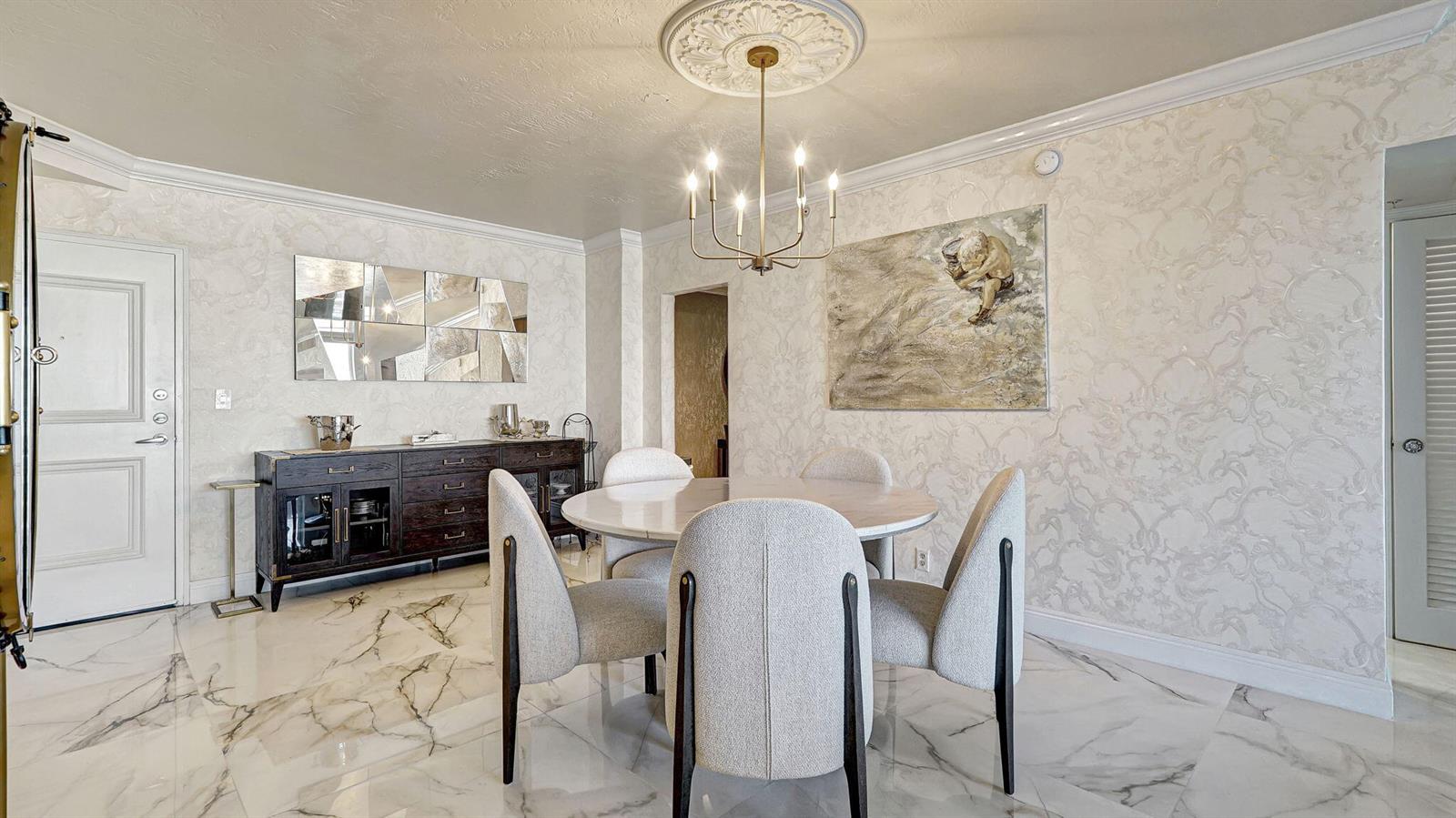 A dining room features a round table, four upholstered chairs, a chandelier, and marble flooring — 3000 S Ocean Drive # 920, Hollywood FL 33019, HOLLYWOOD, FL