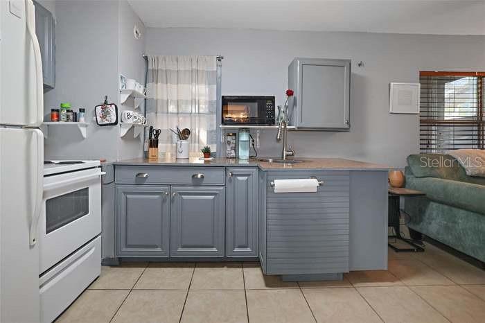 A kitchen features grey cabinets, a white stove, and a microwave above the counter — 2650 25TH AVENUE N, ST PETERSBURG, FL