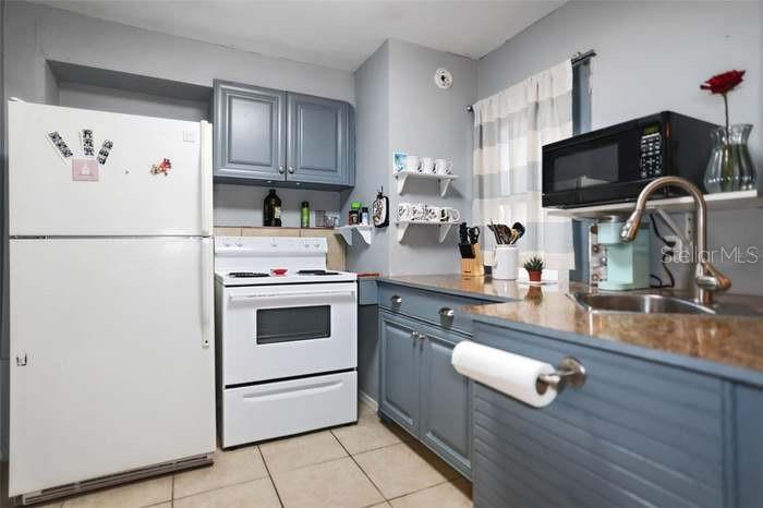 A kitchen features blue cabinets, white appliances, a granite countertop, and a stainless steel sink — 2650 25TH AVENUE N, ST PETERSBURG, FL