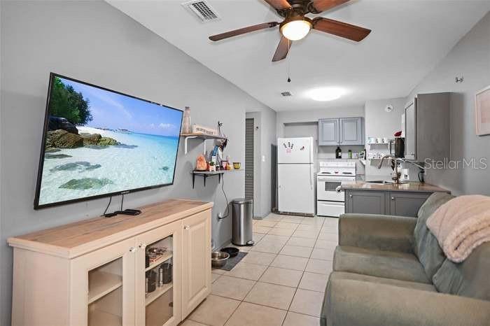 A living room with a television, light wood media console, and an adjacent kitchen area — 2650 25TH AVENUE N, ST PETERSBURG, FL
