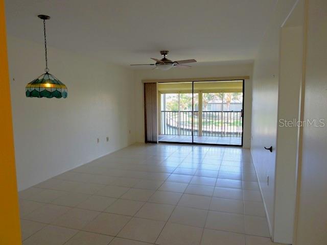 An empty room with white walls, tiled floors, a ceiling fan, and a sliding glass door — 1433 MEDITERRANEAN DRIVE UNIT C, PUNTA GORDA, FL